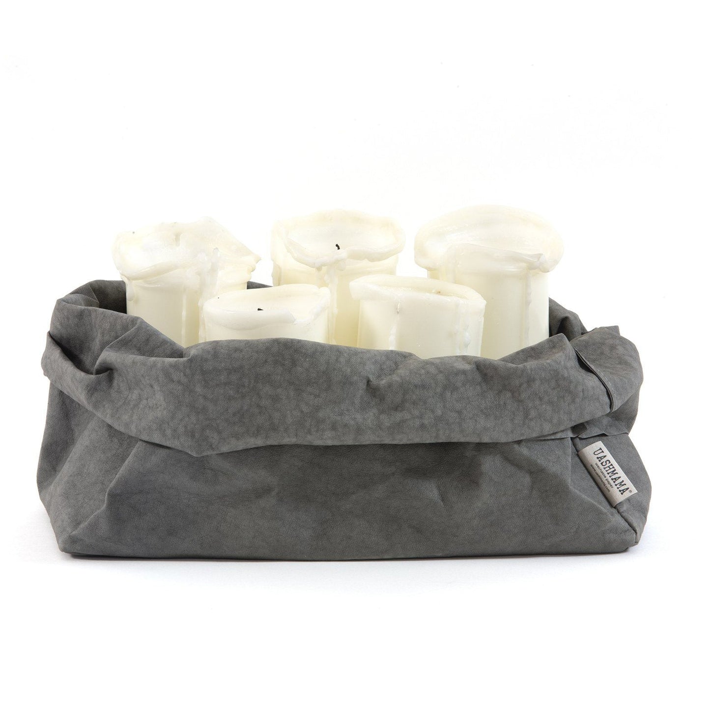 A dark grey oblong washable paper tray is shown. The top is rolled down and the UASHMAMA logo label is shown on the bottom right corner of the bag. The tray is shown holding 5 white pillar candles.